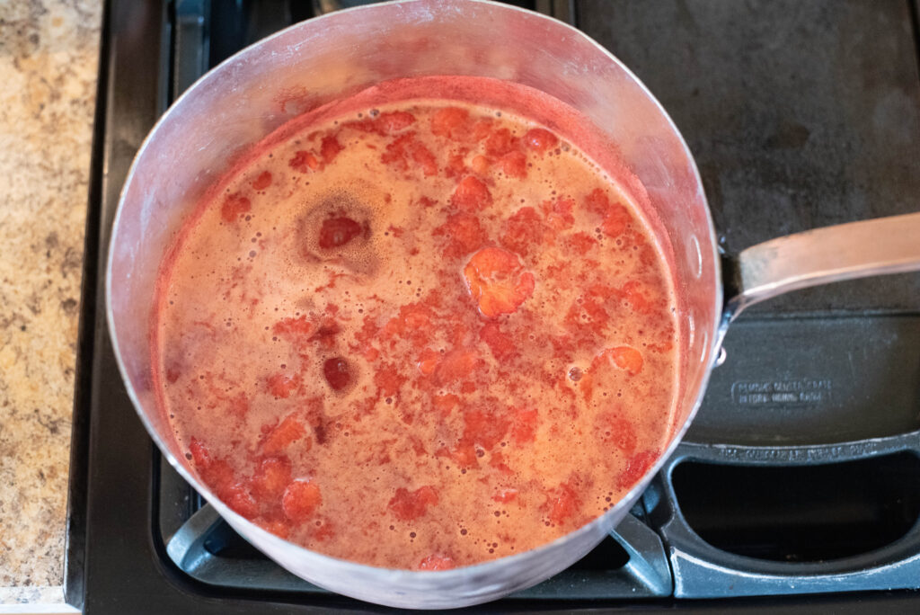 Crushed strawberries simmering for low-sugar strawberry jam