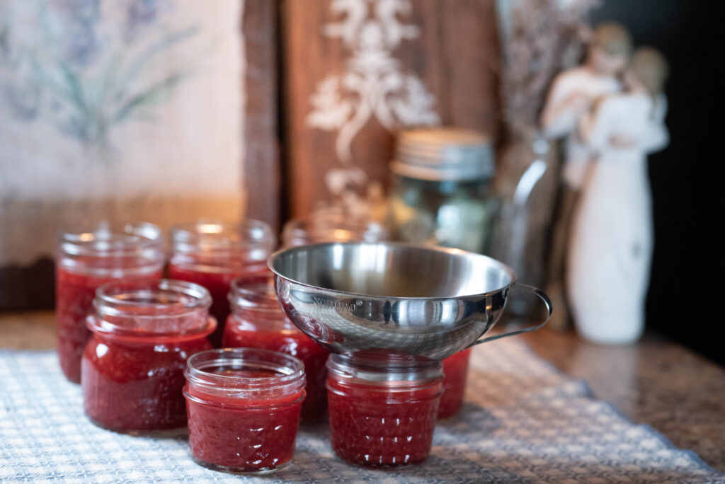 Low-sugar strawberry jam ladled into clean jars waiting to be processed