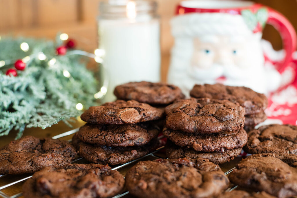 stack of chocolate sourdough cookies with Santa mug, candle and wreath in the background