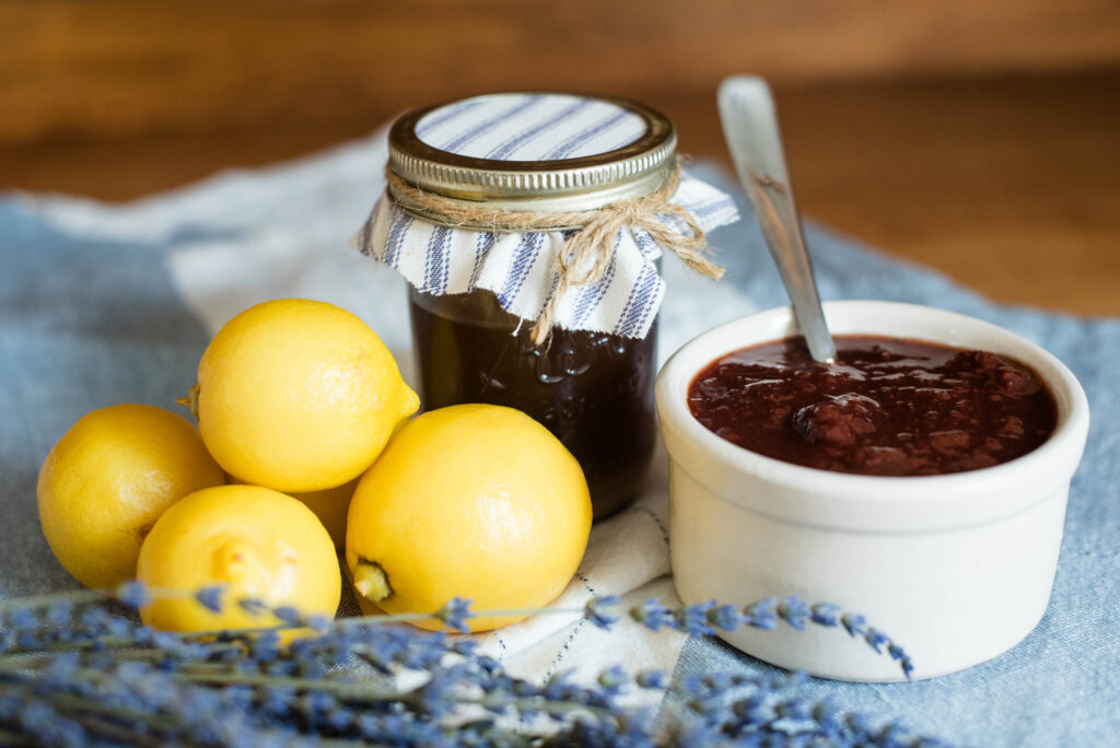 Whole lemons, jar of homemade pectin and bowl of strawberry jam