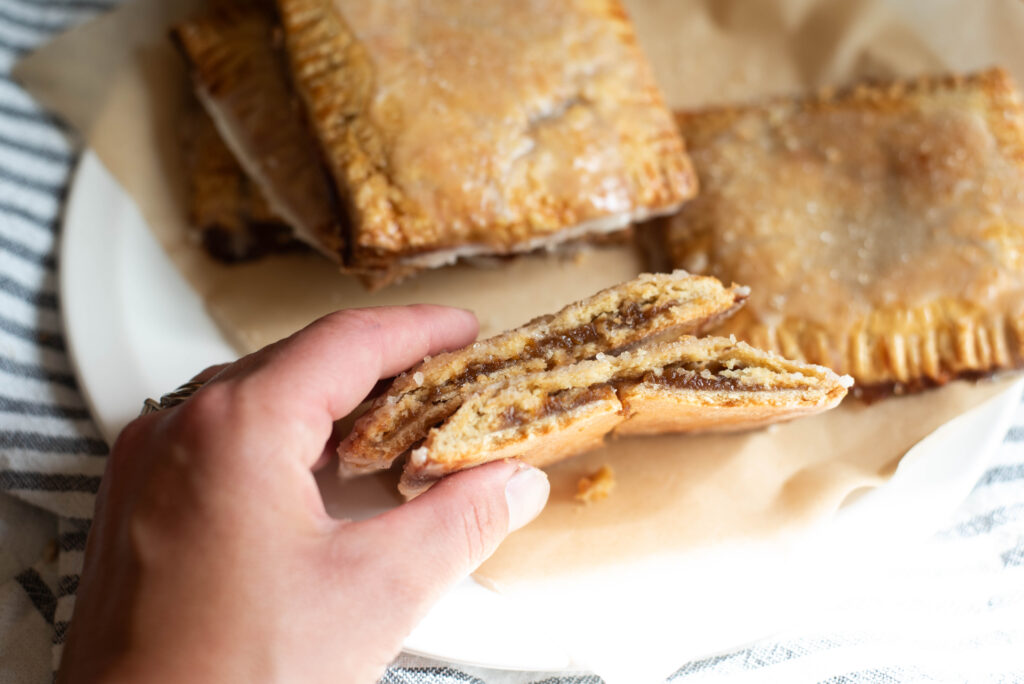 Hand holding pumpkin hand pies cut in half