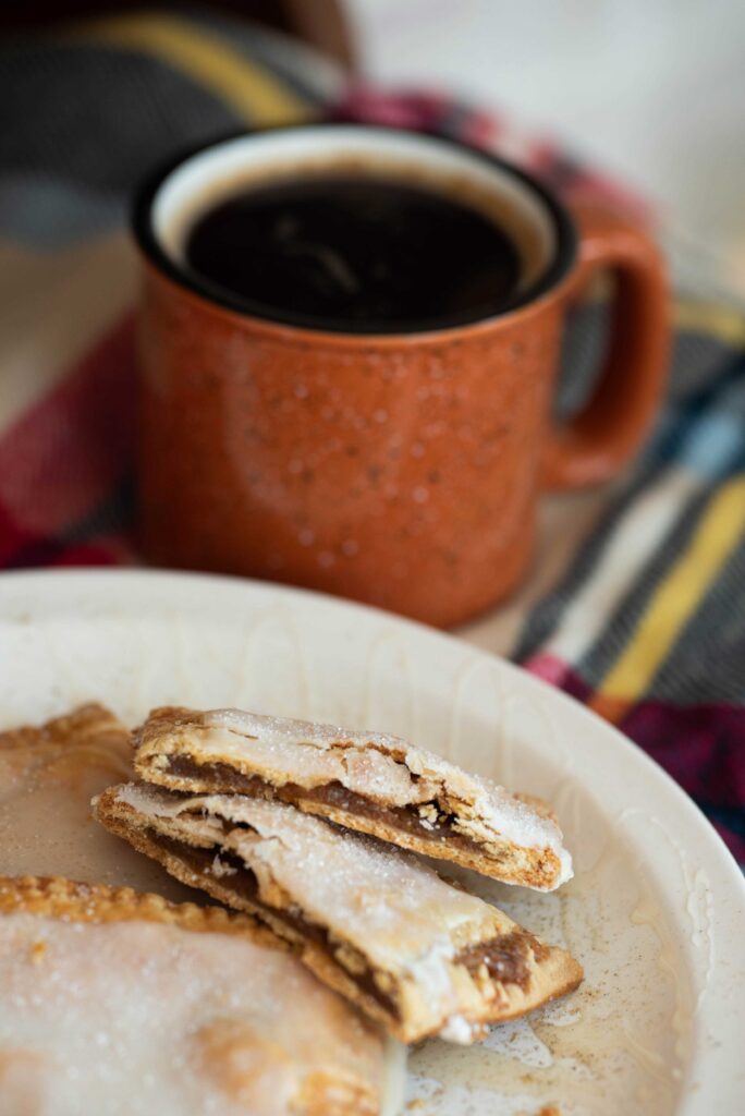Pumpkin hand pies on a plate with coffee cup in background