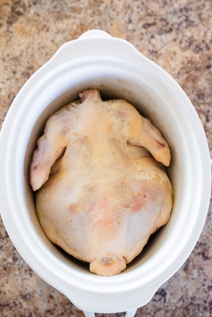 Raw whole chicken in a slow cooker