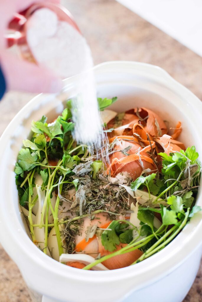 Salt being poured with veggie scraps and chicken