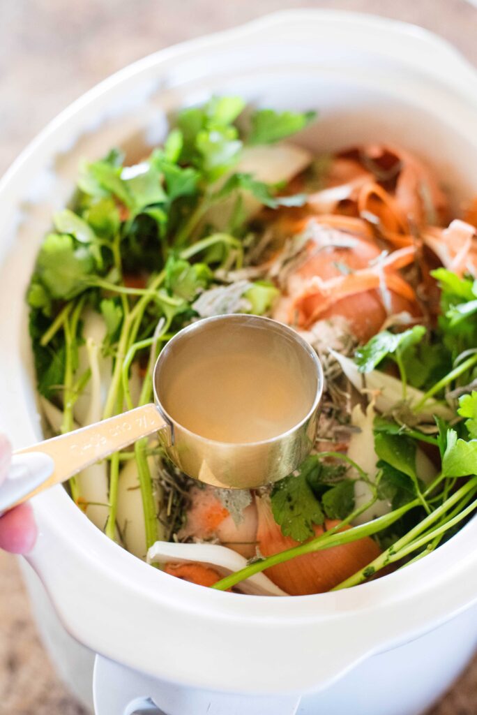 Apple cider vinegar being added to veggie scraps and chicken