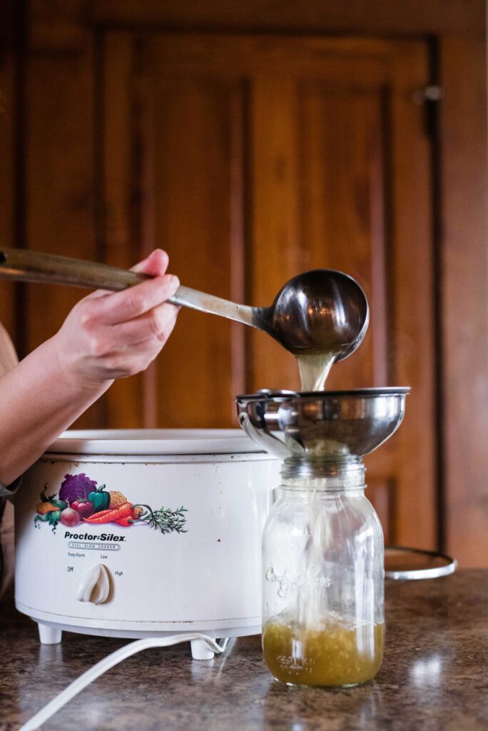 Bone broth being poured into glass jar