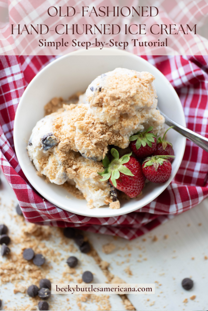 Bowl of hand-churned ice cream with strawberries set on a gingham table cloth.