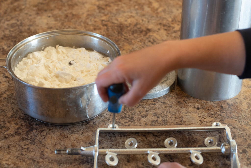 Woman tightening screws on a dasher for making homemade ice cream