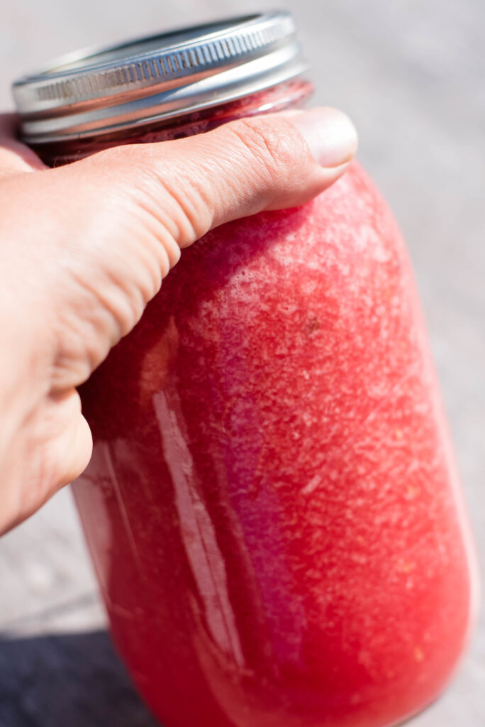 Jar of watermelon soup being shaken.