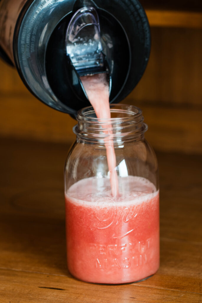 Watermelon puree being poured into a quart jar.