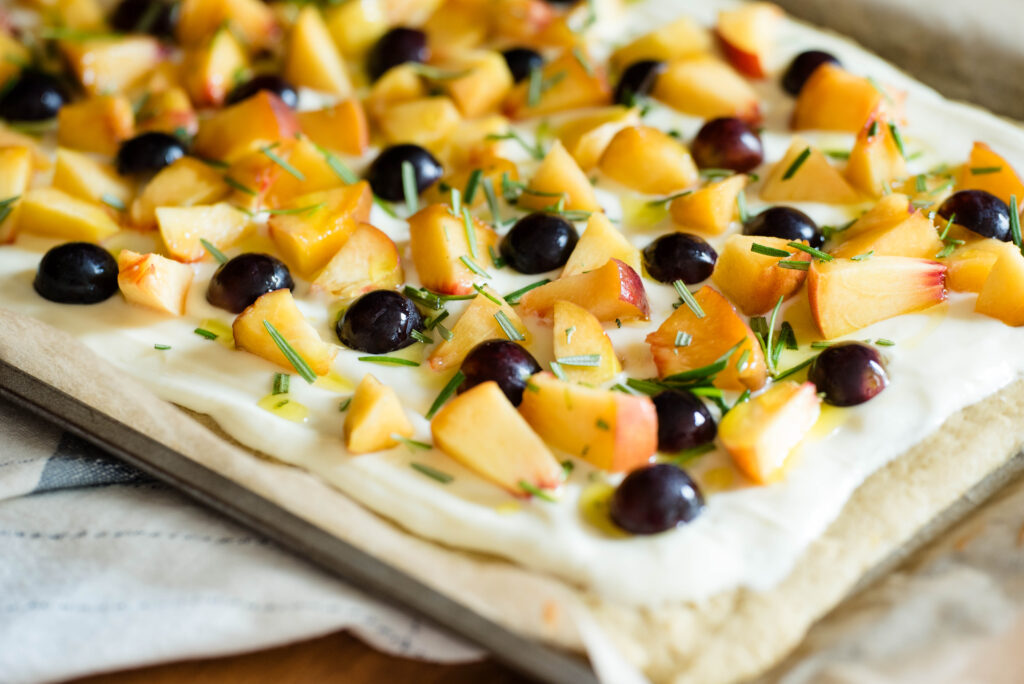 Fruit pizza with peaches and grapes with fresh rosemary and olive oil drizzle