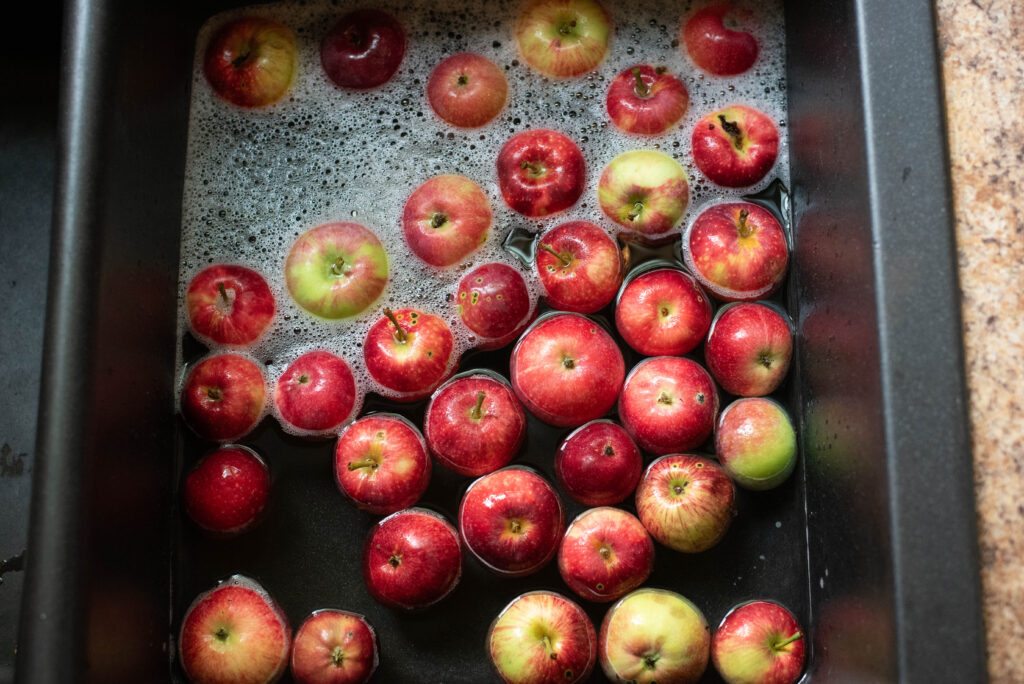 Apples being washed in a sink.