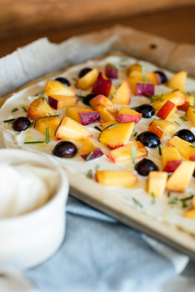 Pan of fruit pizza with peaches and grapes