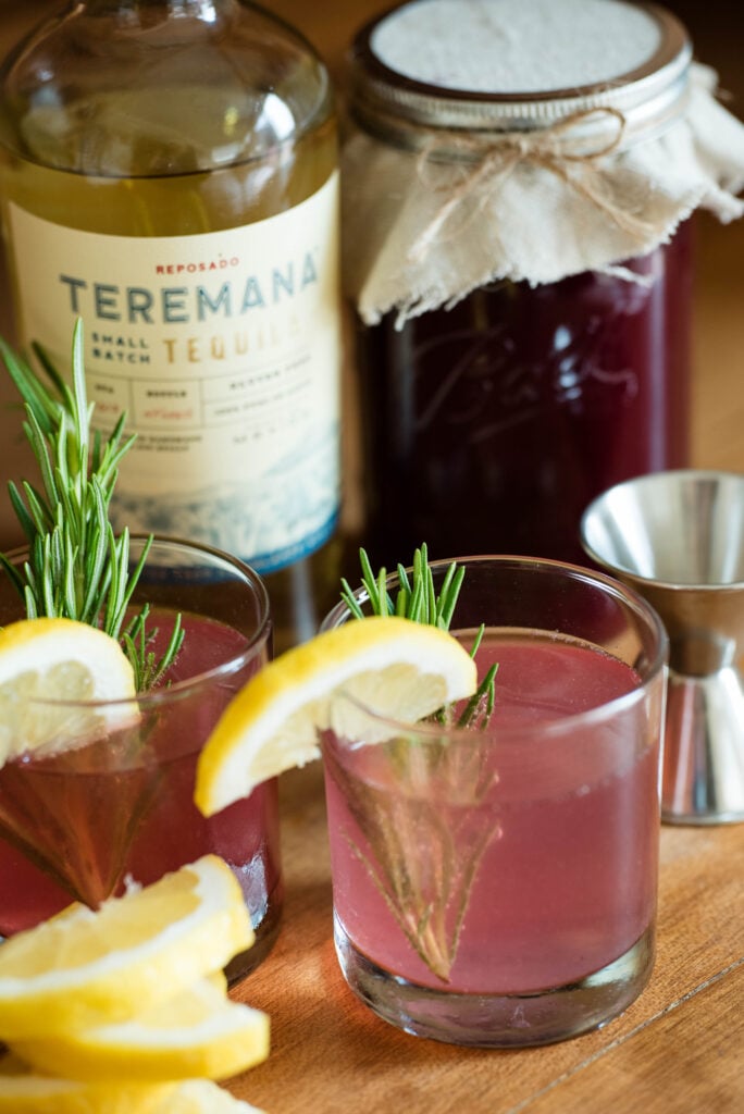 Cocktails made with homemade shrub garnished with lemon and fresh rosemary.