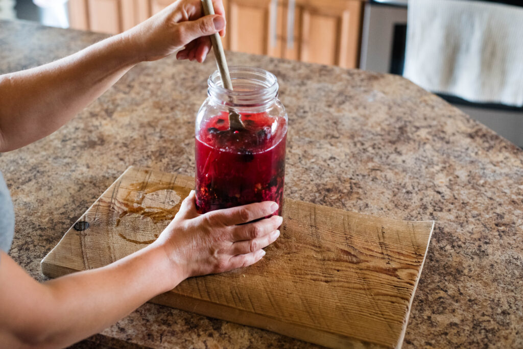 Jar of homemade shrub being stirred.