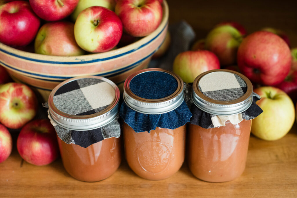 Jars of applesauce covered with cozy scrap fabric for gifting.