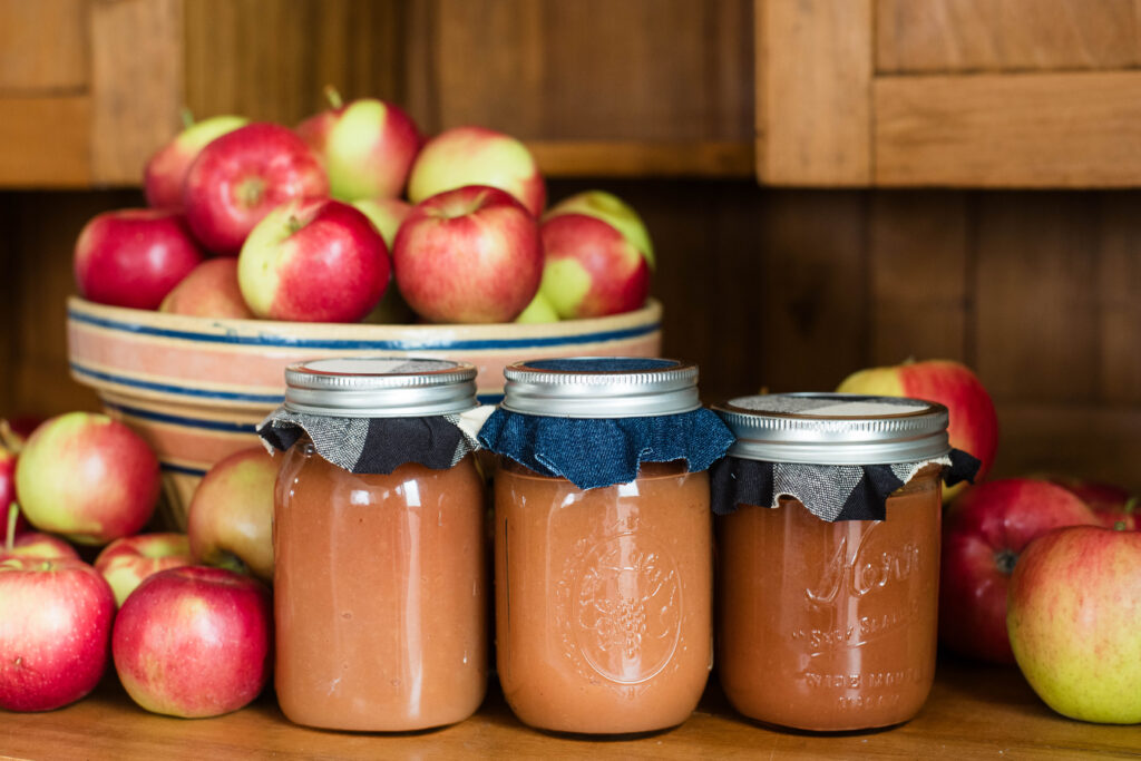 Bowl of apples with jars of applesauce.