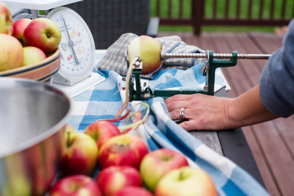 Woman using an apple peeler, corer, slicer device for apples.