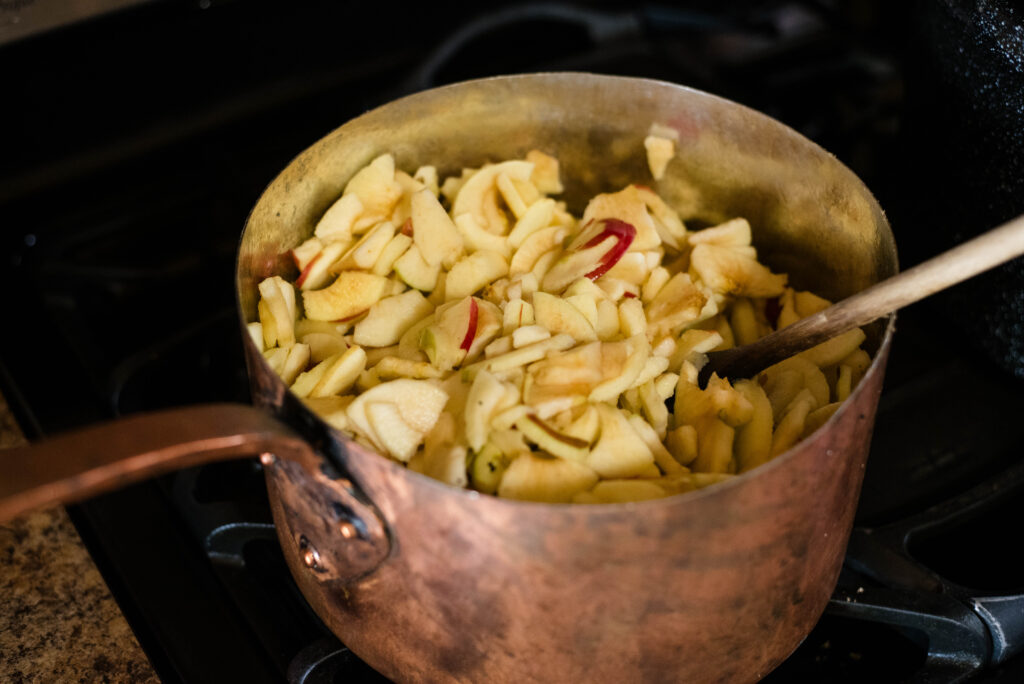 Fresh chopped apples cooking in pot on stovetop.