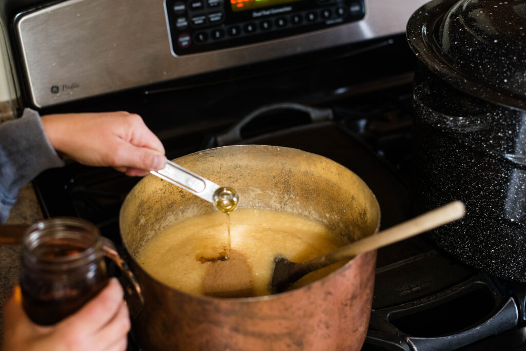 Vanilla and cinnamon being added to freshly made applesauce.