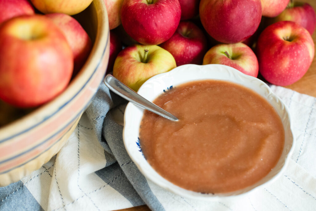Fresh apples with bowl of simple no sugar applesauce.