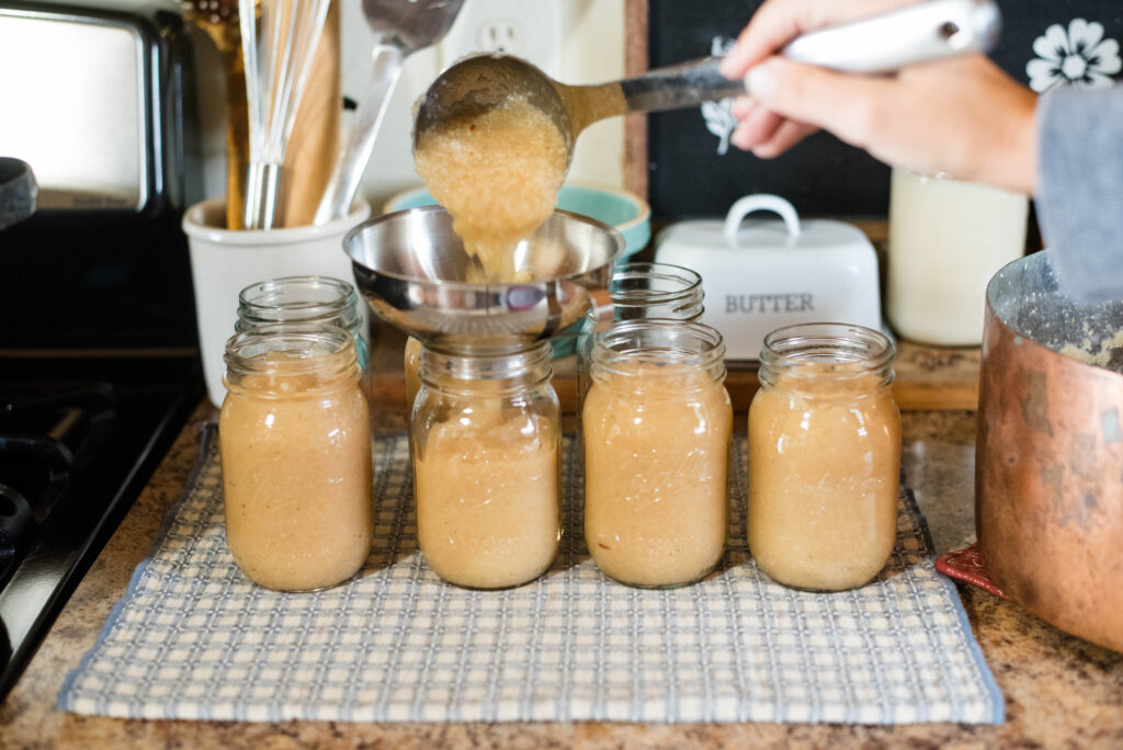 Applesauce being ladled into jars.