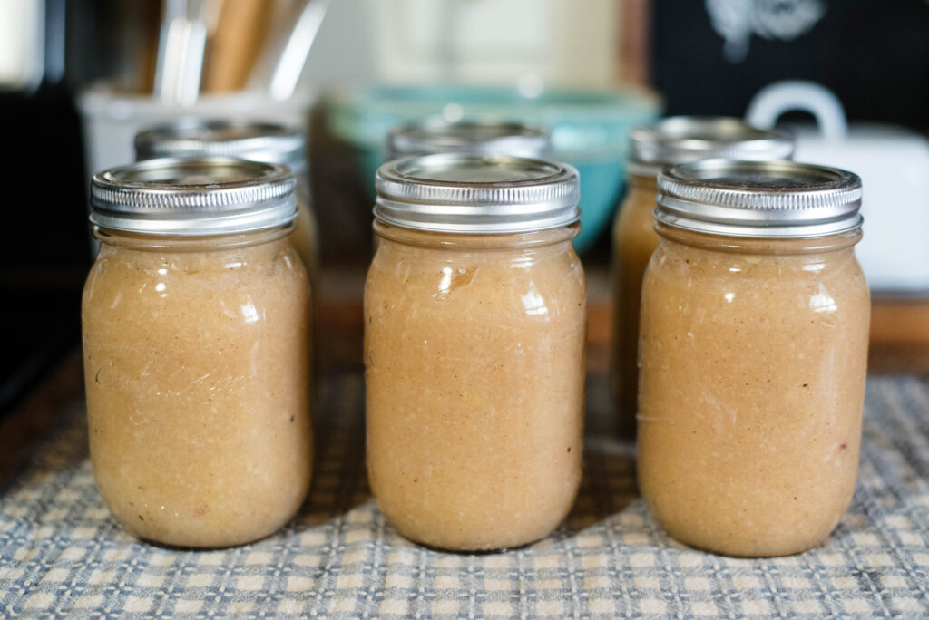 Freshly canned jars of applesauce resting on towel.