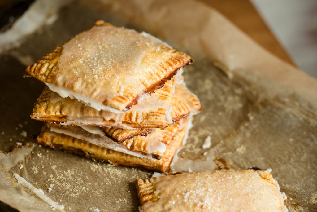 Homemade pumpkin hand pies stacked on a baking sheet.