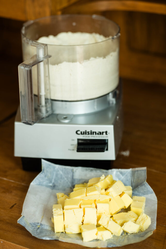 Cubed butter waiting to be mixed into flour mixture in a food processor.