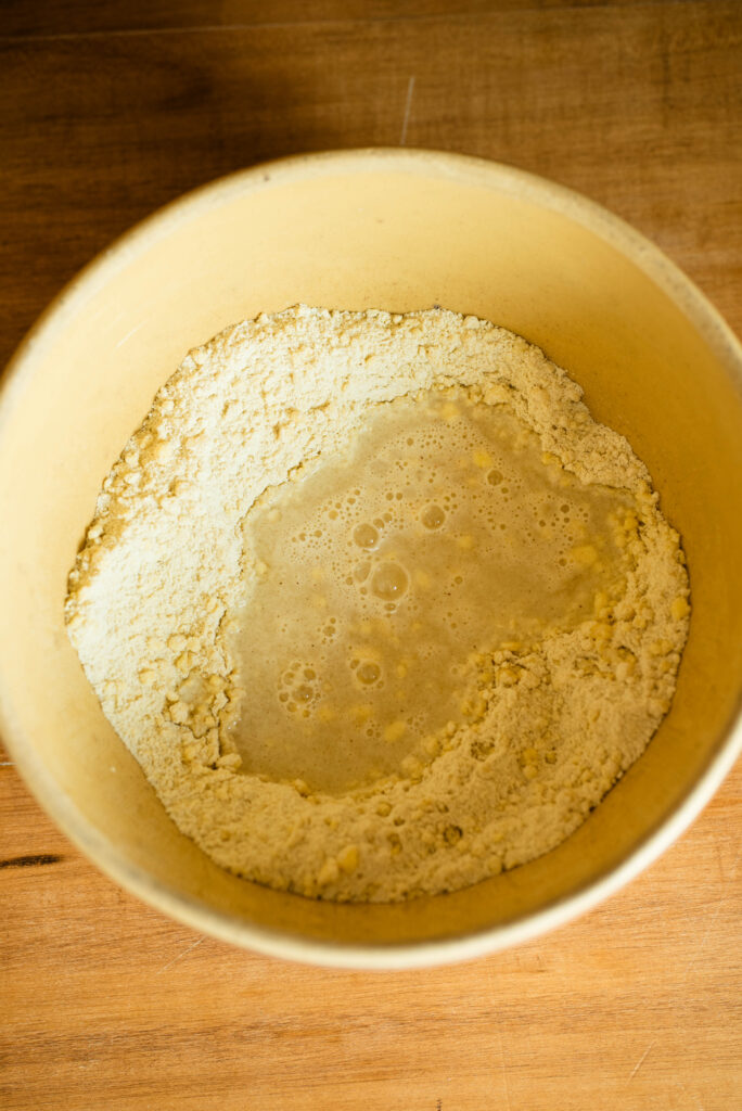 Wet ingredients added to dry ingredients in a mixing bowl.