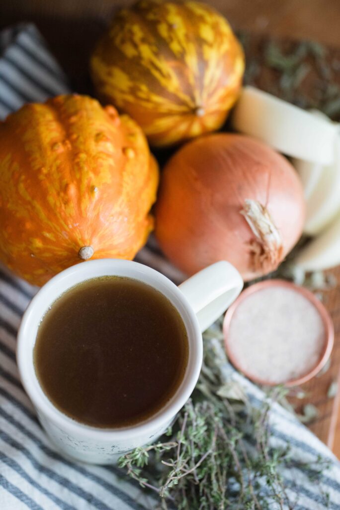 Cup of bone broth with a pumpkin, onion, thyme and salt.