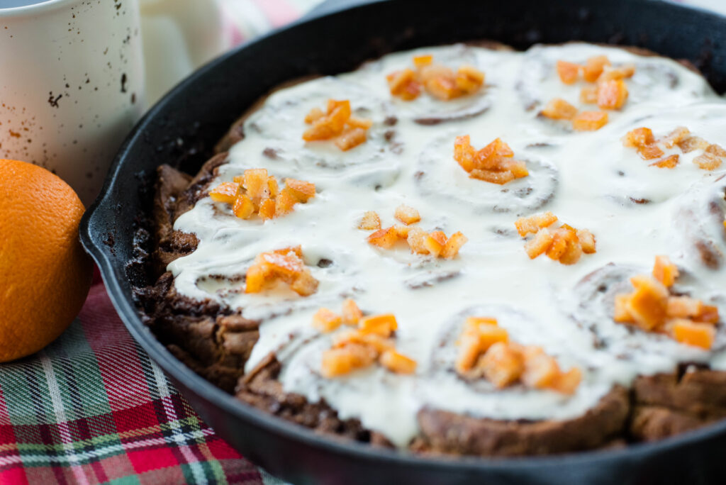 sourdough gingerbread cinnamon rolls with cream cheese frosting and candied orange peels