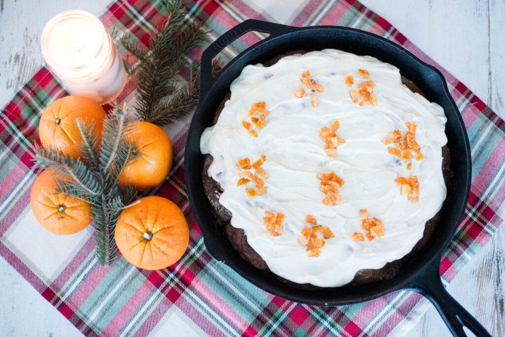 Sourdough gingerbread cinnamon rolls with salted candied orange peel in a cast iron skillet