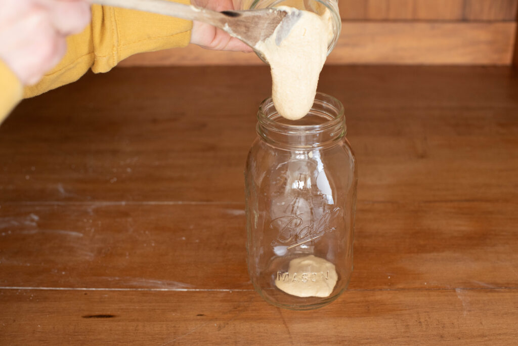sourdough starter being discarded into clean jar