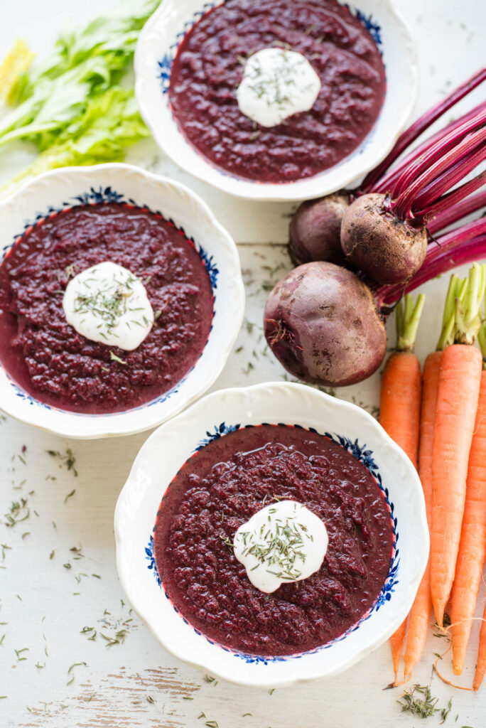 Homemade beet soup pictured with fresh beets, carrots and dried thyme