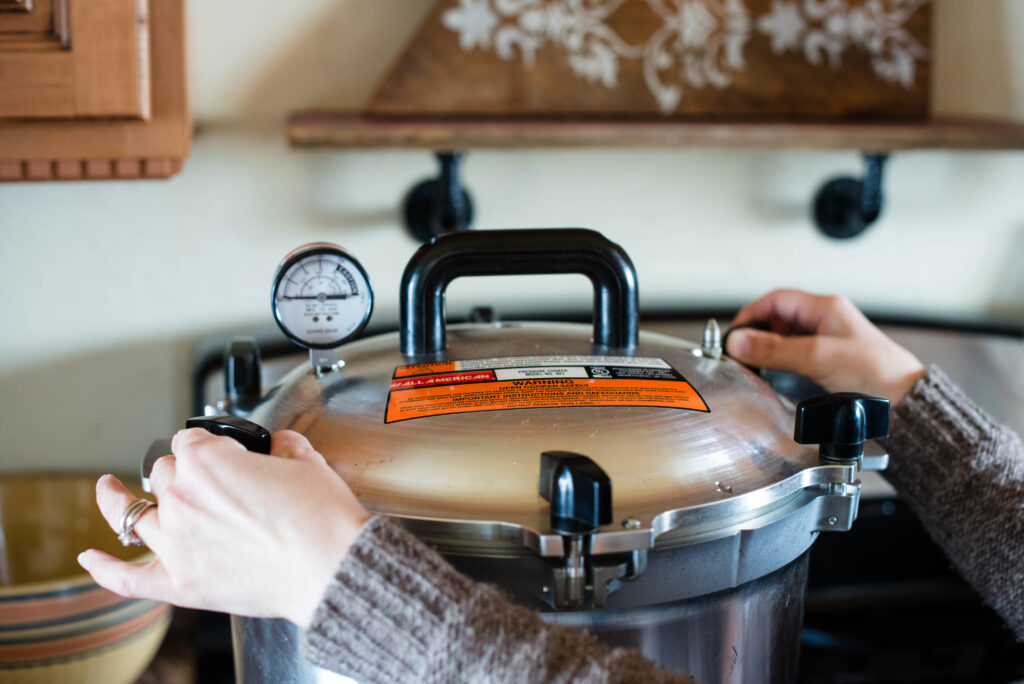 Tightening wing nuts on lid for pressure canning.