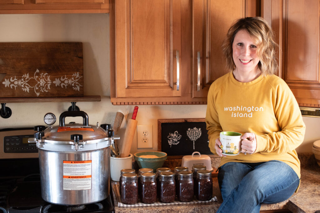 Woman with a pressure canner and jars of beans