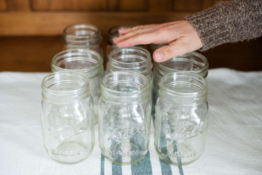 Woman's hand checking for chips in the rim of glass Mason jars