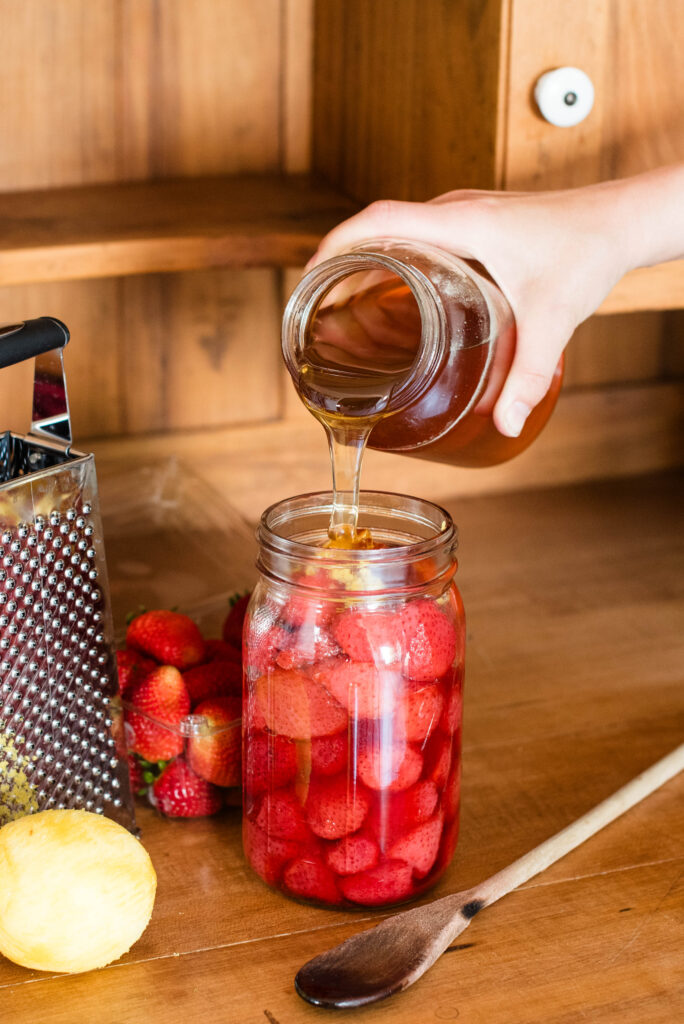 Fermented strawberries with honey being stirred together