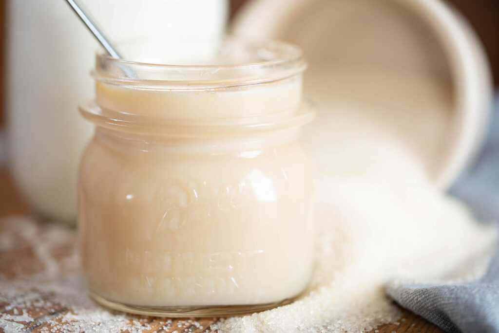 Homemade sweetened condensed milk in a glass jar.