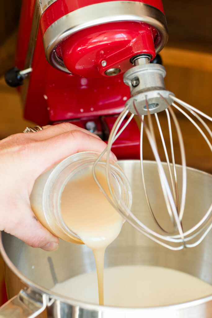 Sweetened condensed milk being poured into a mixer.
