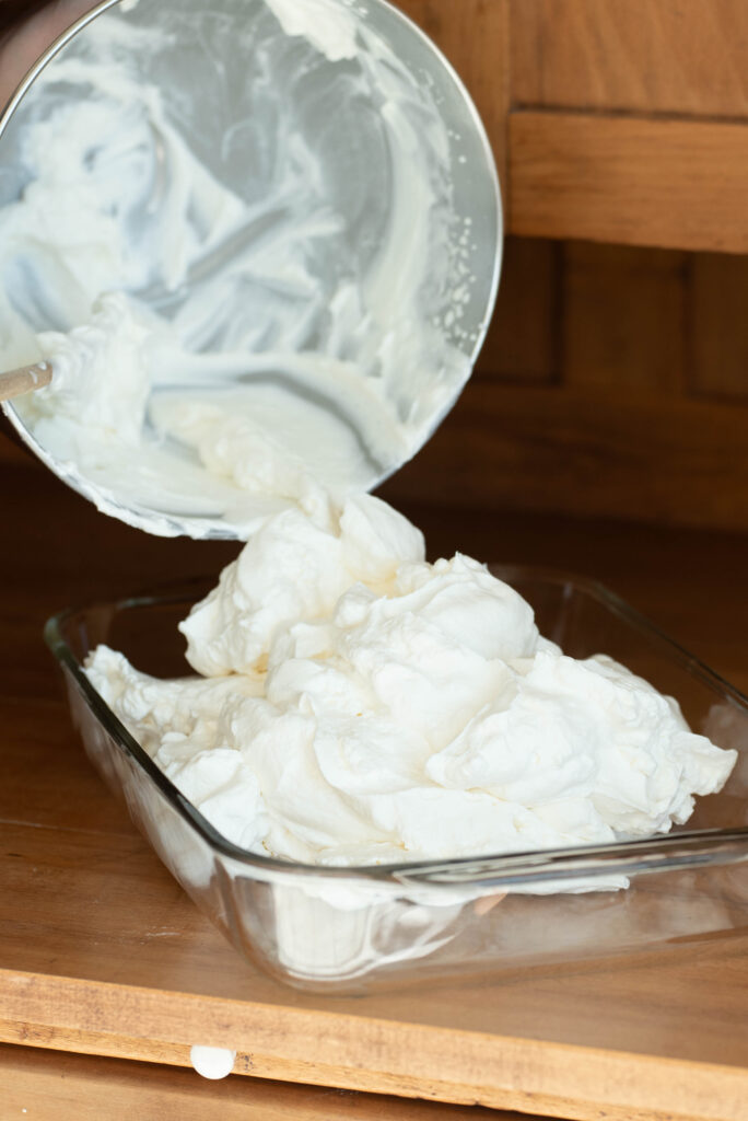 Homemade vanilla ice cream scooped into pan.