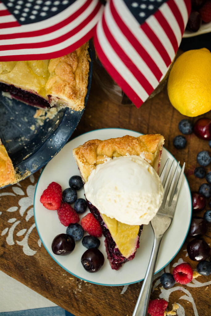 Slice of mixed berry pie with honey and fresh fruit