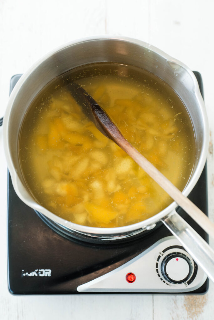 Sugar and lemon peel mix boiling with water.