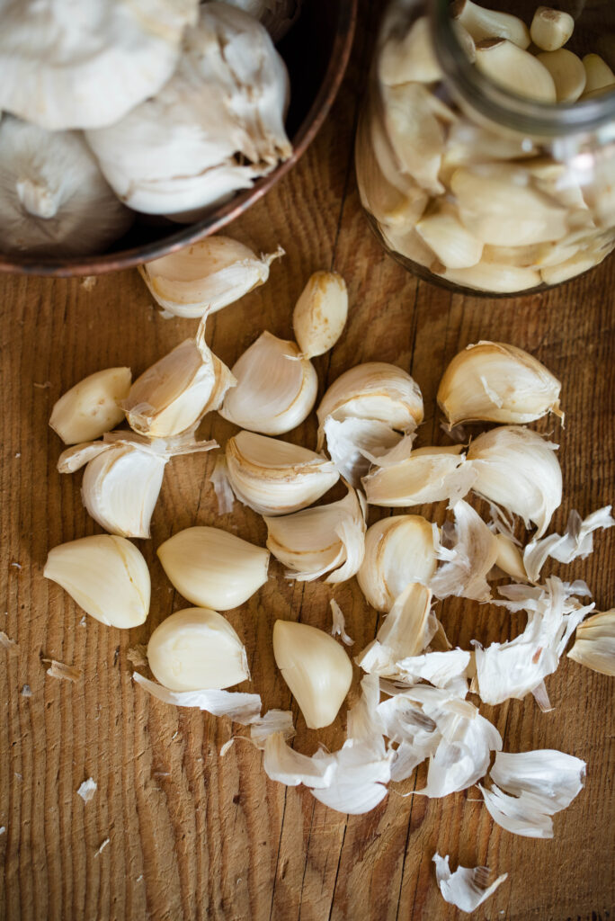 Fresh garlic cloves on cutting board with skins.