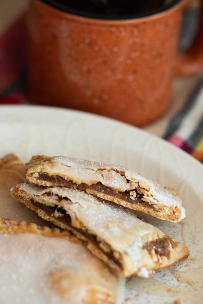 Homemade pumpkin hand pies cut in half with a cup of coffee.