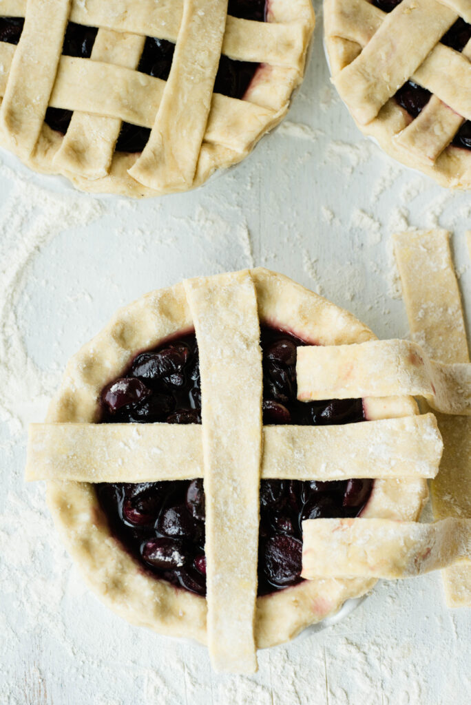 Cherry pie with first and third strips of pie dough pulled back for lattice top crust.