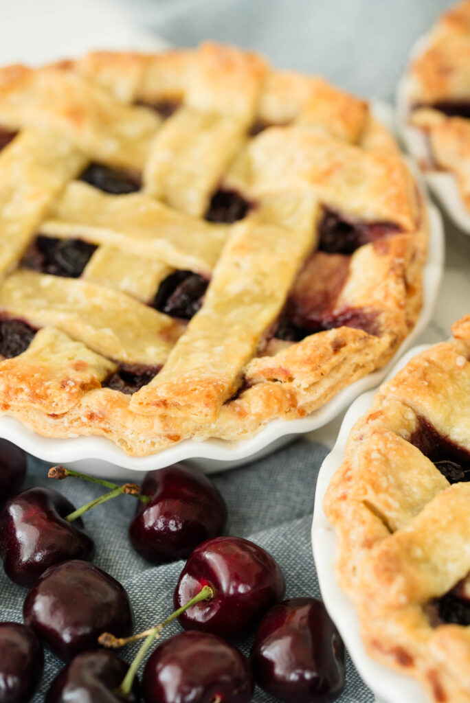 Sourdough Door County cherry pies with lattice tops and fresh cherries.