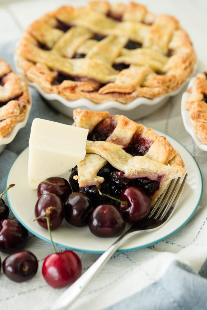 Sourdough door county cherry pies with a slice, wedge of cheese and fresh cherries.
