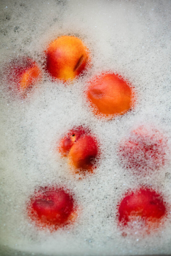Peaches being washed in soapy water.